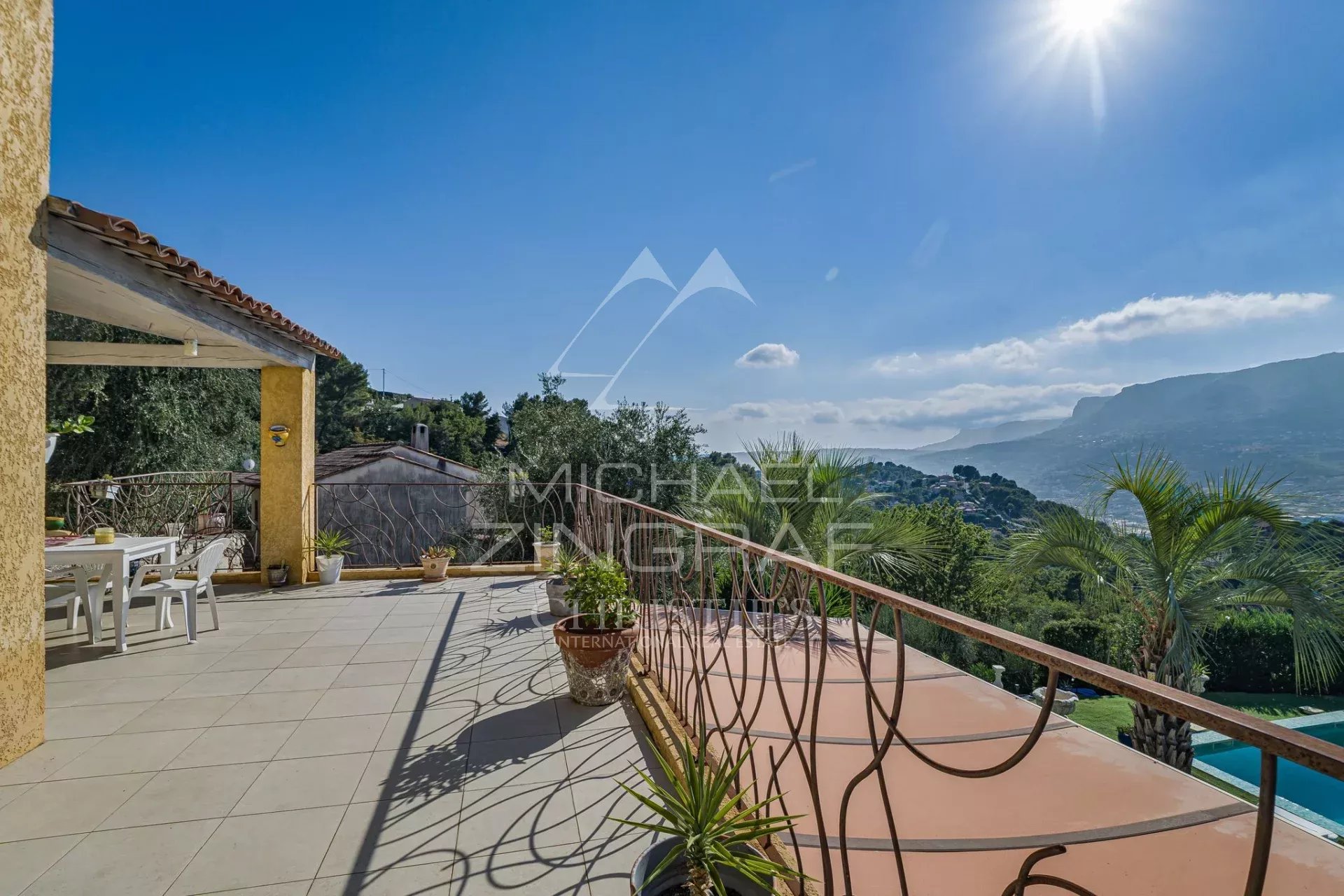 Propriété familiale à Colomars Terrasse d'une propriété à Colomars avec vue sur les collines et montagnes, piscine visible.