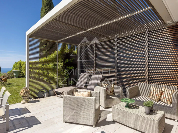 Terrasse d'un appartement à Nice avec mobilier en osier et vue sur la verdure.