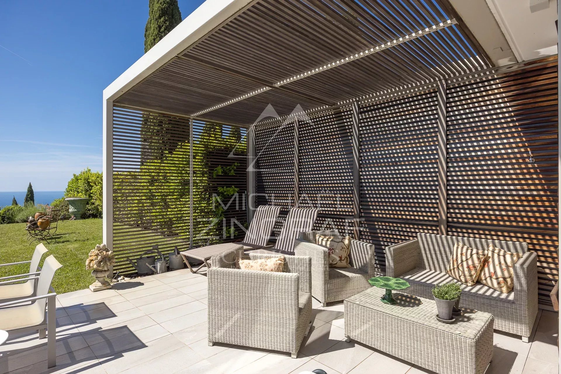 Terrasse d’un appartement d’exception à Nice Terrasse d'un appartement à Nice avec mobilier en osier et vue sur la verdure.