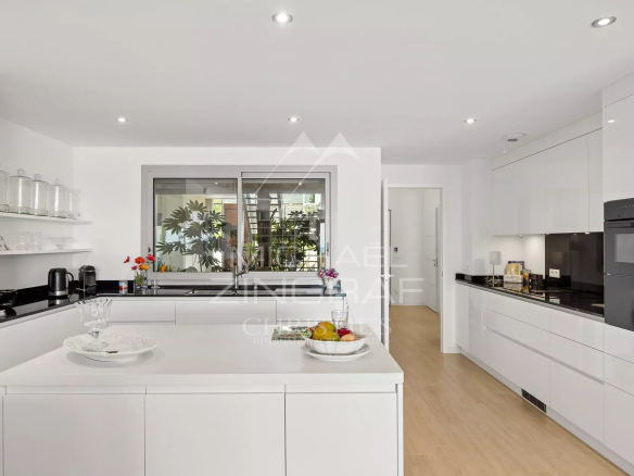 Cuisine moderne et lumineuse d'un appartement à Nice, avec îlot central et vue sur un jardin.