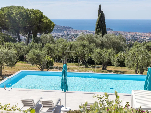 Vue d'un jardin avec piscine et oliviers, surplombant la mer à Nice.