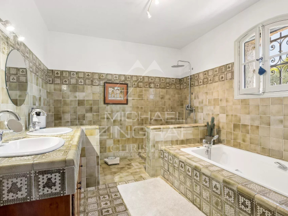 Salle de bain spacieuse avec baignoire et double vasque, carrelage décoratif.