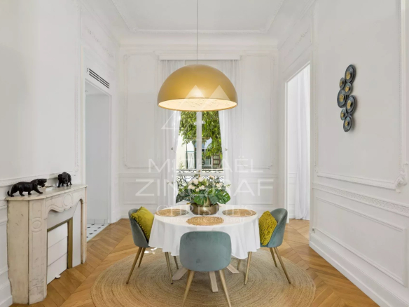 Dining room of an old apartment with parquet flooring, moldings and fireplace in Nice.