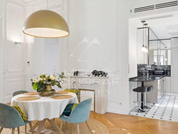Dining room in an elegant apartment with a round table and open-plan kitchen, Nice