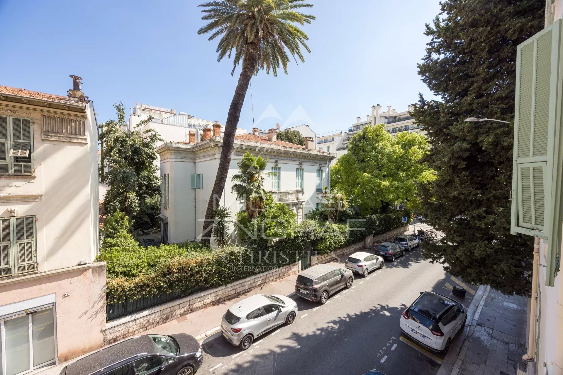 Old building in Nice View of an old building surrounded by trees in Nice, with cars parked on the street.