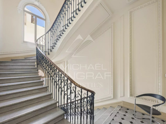 Staircase of an elegant old building with wrought iron balustrade and ornate walls.