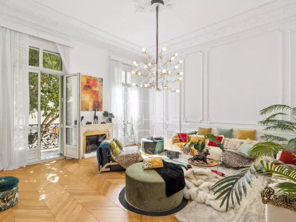 Bright living room of an old apartment in Nice with parquet flooring and moldings.
