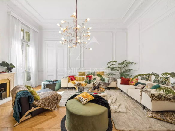 Bright living room of an old apartment in Nice with parquet flooring, moldings and fireplace.