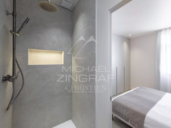 Modern bathroom with shower and adjacent bedroom in a renovated apartment.