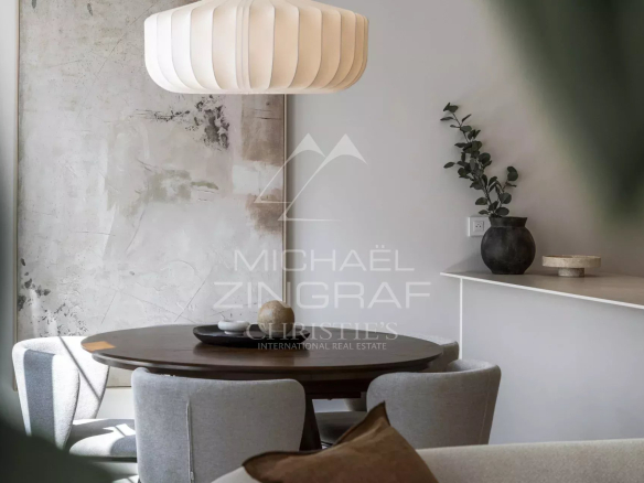 Interior of a renovated apartment with a round table and chairs, decorated with plants.