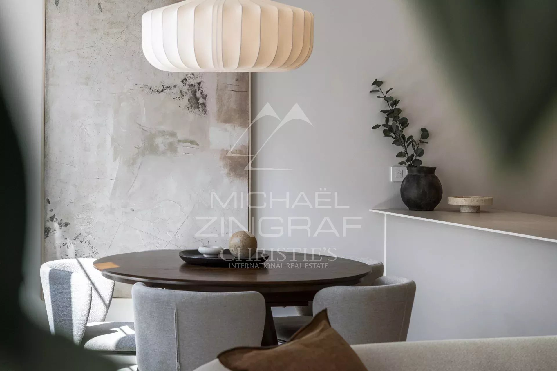 Interior of a renovated apartment with a round table and chairs, decorated with plants.
