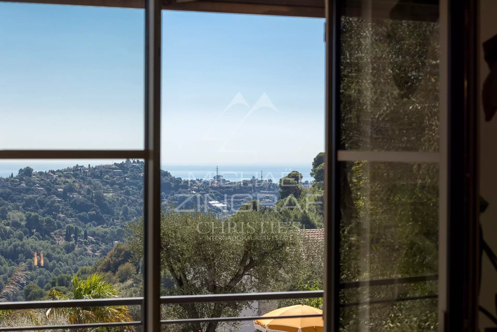 Vue dégagée sur la mer depuis une villa rénovée à Nice, avec un cadre résidentiel verdoyant.