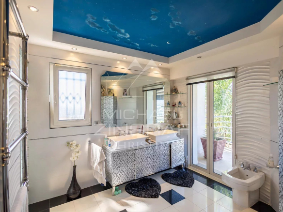 Salle de bain moderne avec un plafond bleu, baignoire et fenêtres donnant sur l'extérieur.