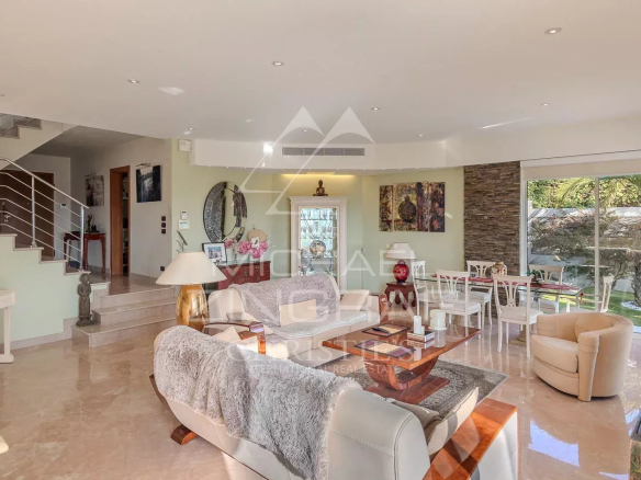 Intérieur d'une villa à Nice avec salon lumineux et baies vitrées, vue sur la mer et les collines.