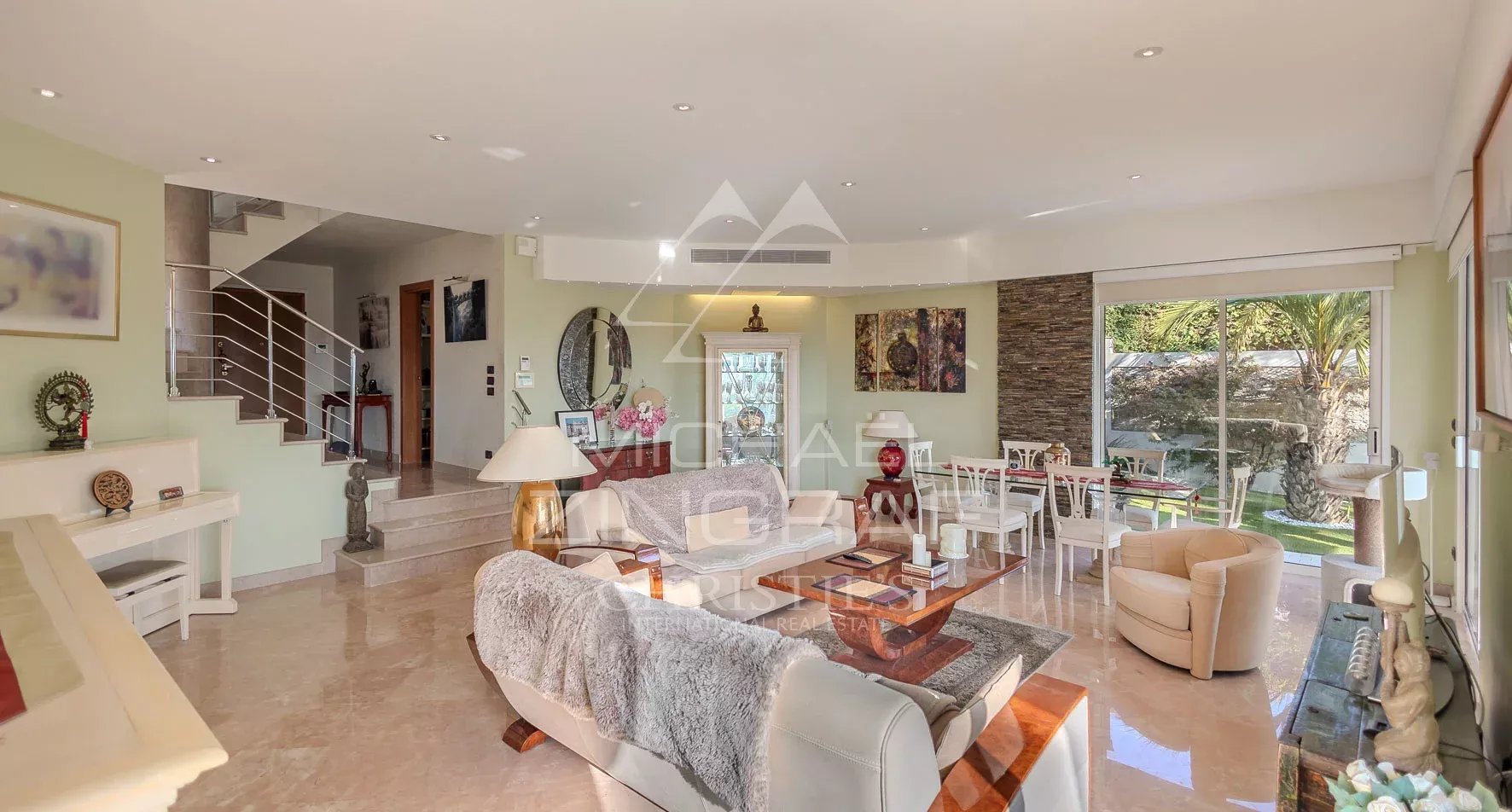 Intérieur d'une villa à Nice avec salon lumineux et baies vitrées, vue sur la mer et les collines.