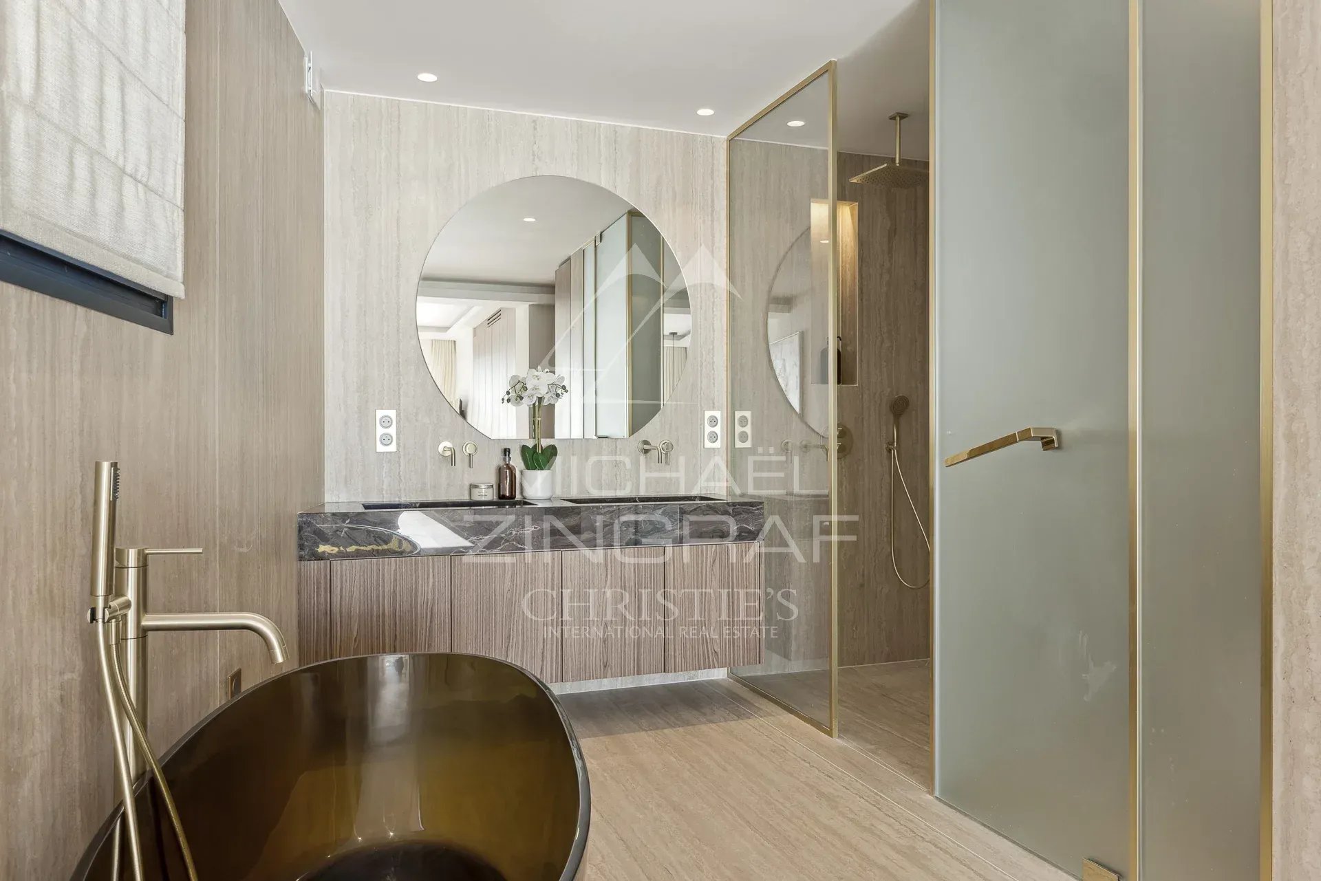 Salle de bain contemporaine Salle de bain moderne avec baignoire dorée et miroir rond, décorée dans des tons neutres.