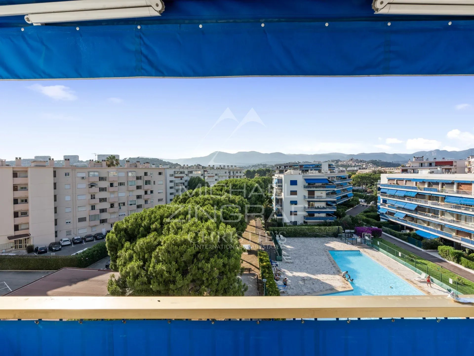 Vue depuis un balcon d'un appartement à Cagnes-sur-Mer, piscine et résidences en arrière-plan.