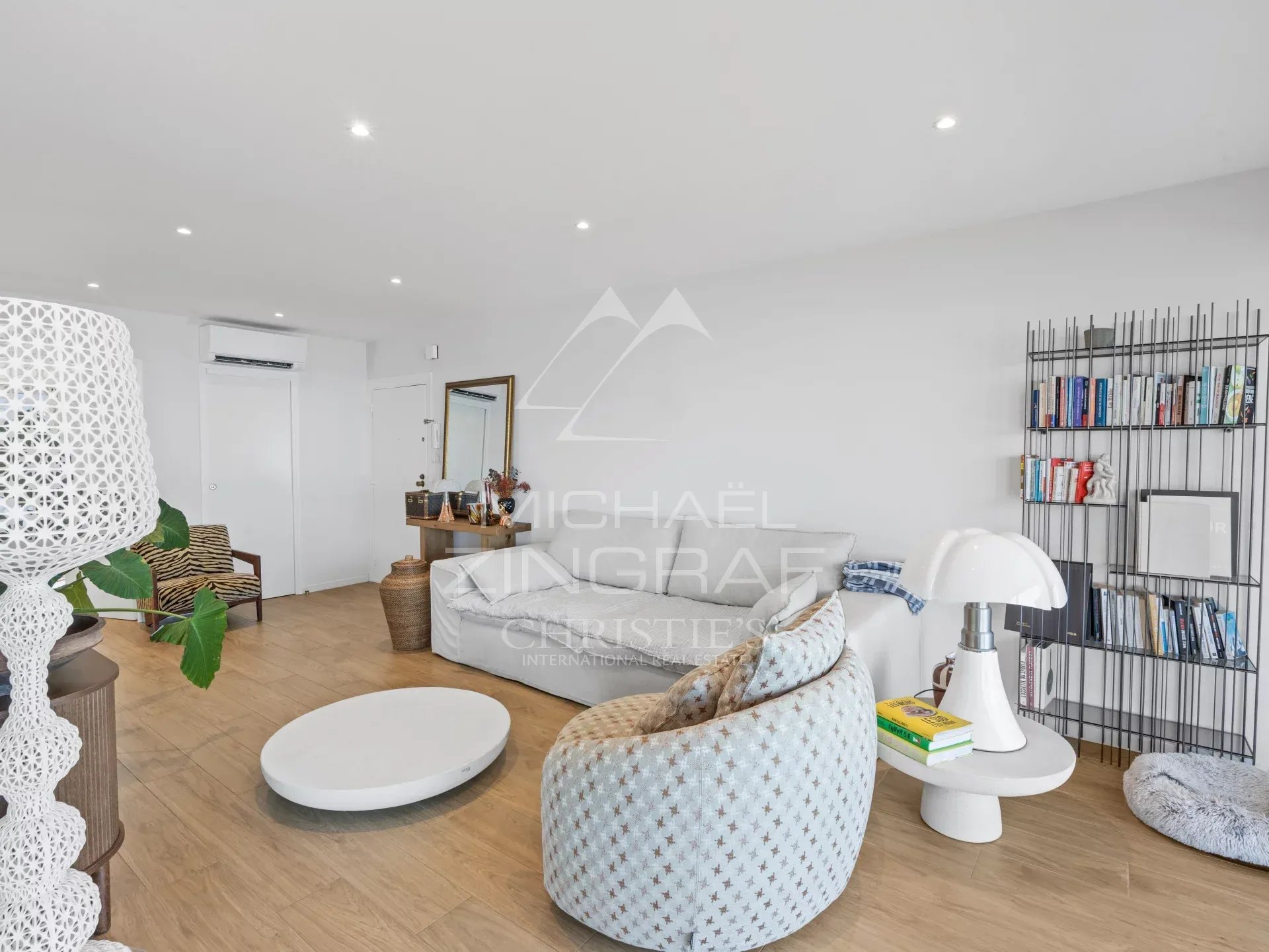 Intérieur d'un appartement moderne avec mobilier contemporain, salon lumineux et bibliothèque.