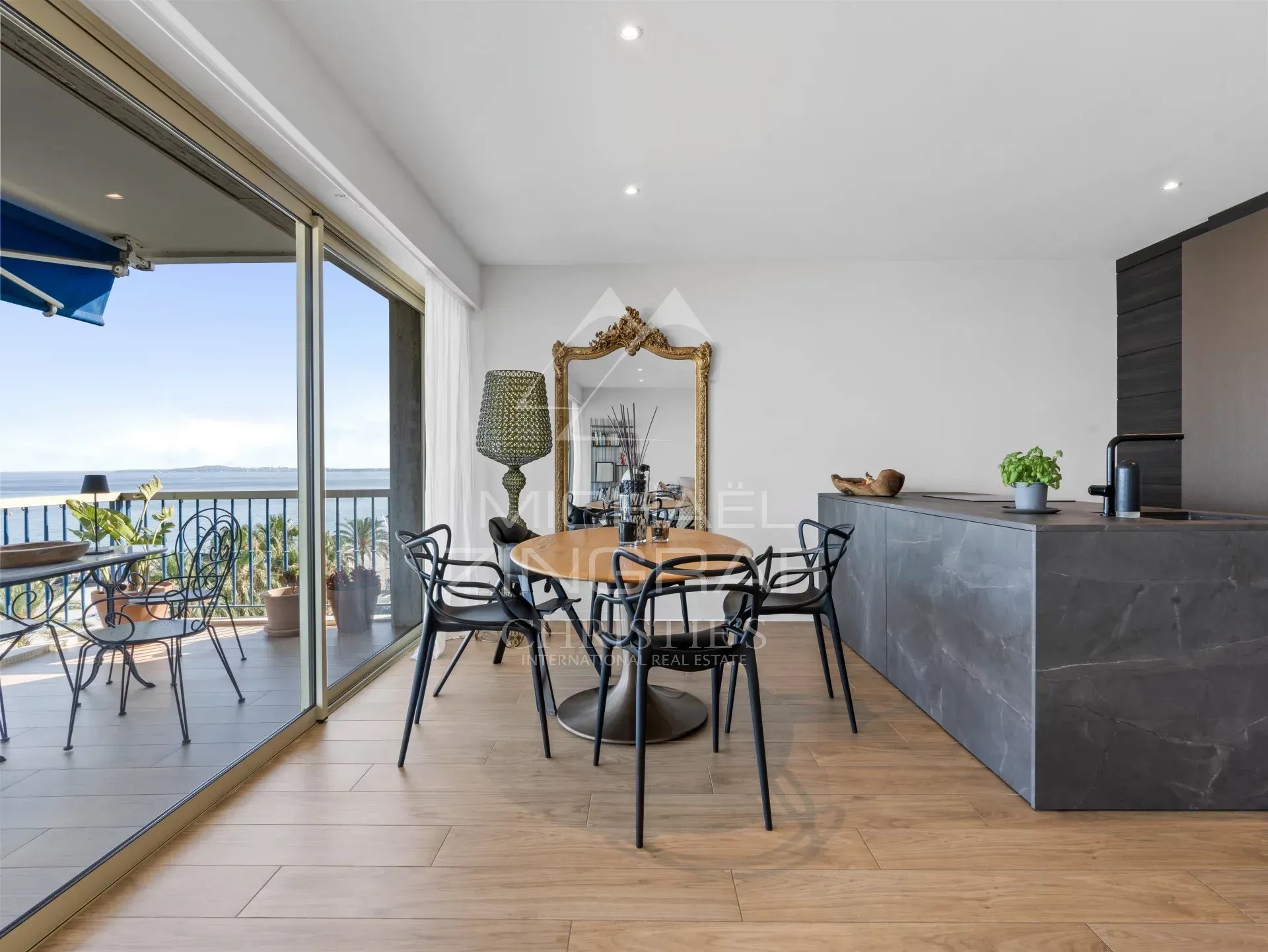 Intérieur d'un appartement moderne avec vue sur la mer à Cagnes-sur-Mer, salle à manger et cuisine ouverte.