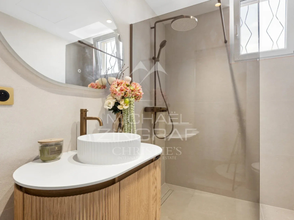 Salle de bain moderne avec douche, lavabo design et décoration florale.