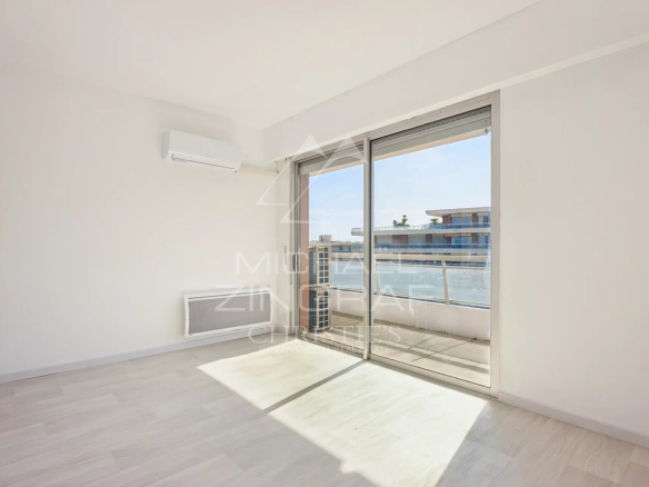 Intérieur d'un appartement lumineux avec une grande baie vitrée et vue sur la mer à Nice Fabron.