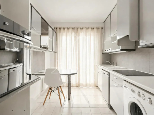 Cuisine moderne et lumineuse avec table, chaises et équipements électroménagers.