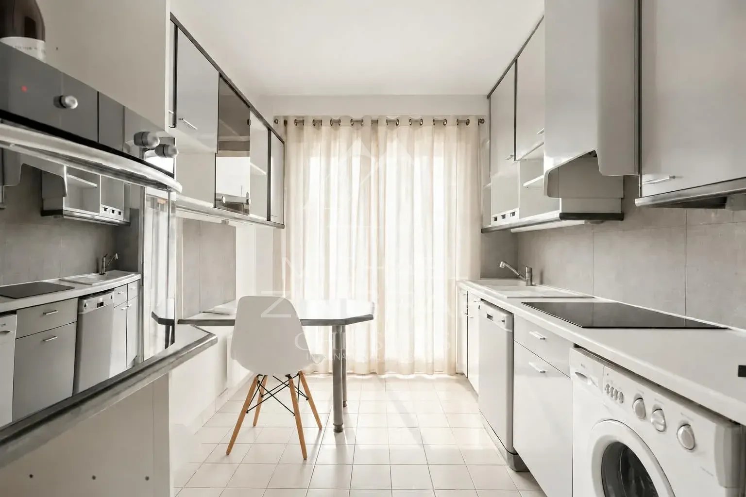 Cuisine d’un appartement à Nice Fabron Cuisine moderne et lumineuse avec table, chaises et équipements électroménagers.