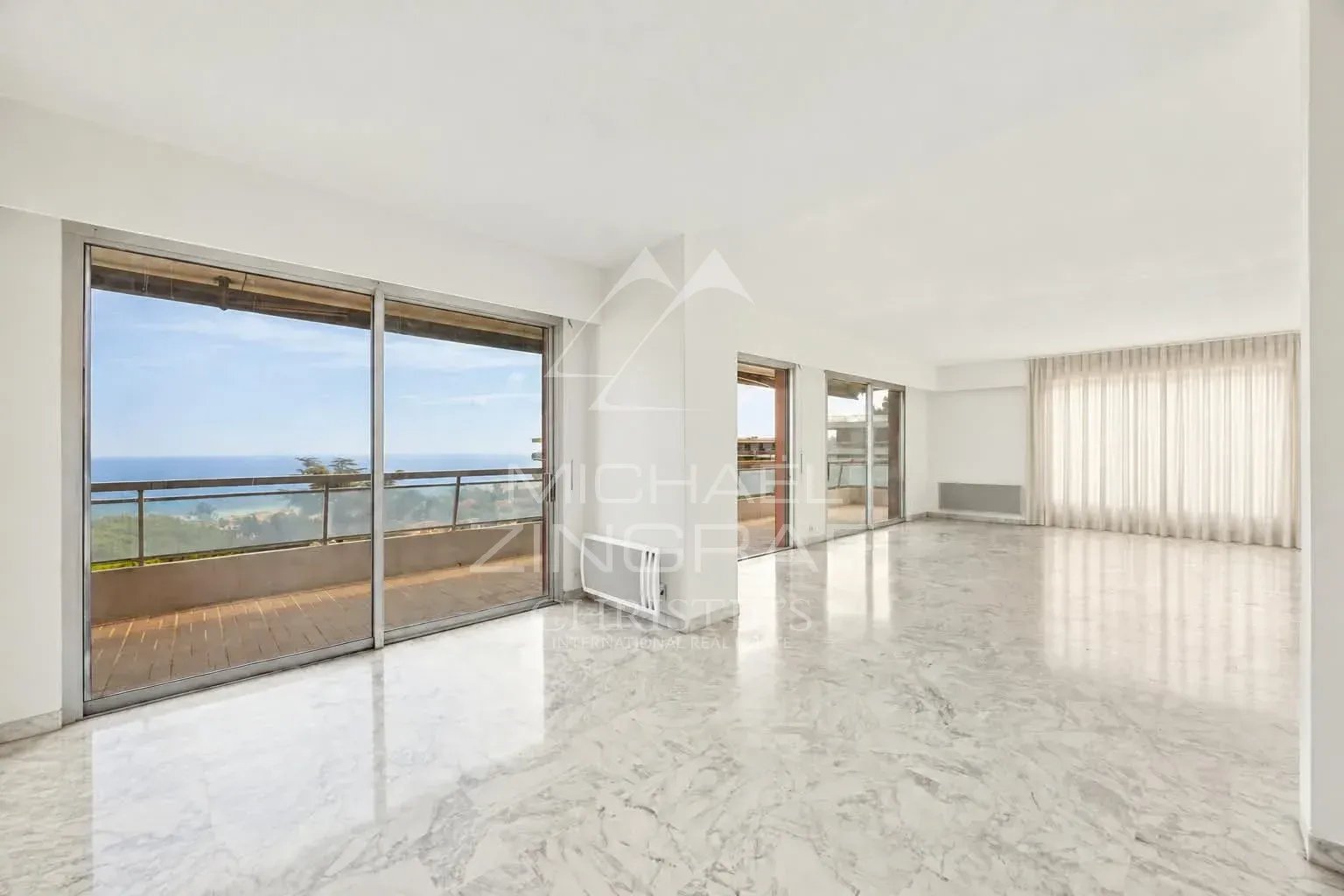 Appartement à Nice Fabron avec vue mer Intérieur d'un appartement spacieux avec vue sur la mer à Nice, grandes fenêtres et sol en marbre.