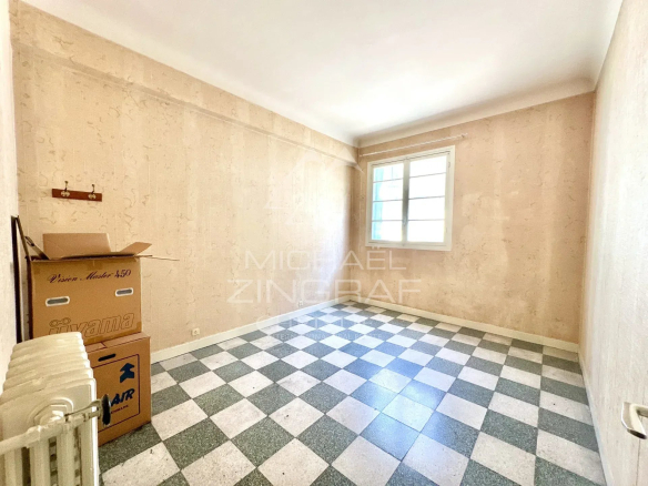 Intérieur d'un appartement vide avec un sol en carreaux noir et blanc, murs clairs.