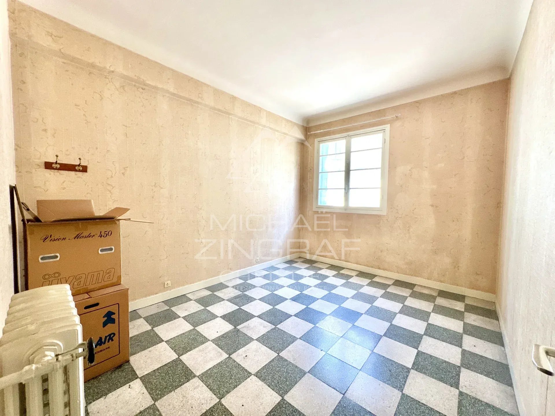 Appartement à réinventer à Nice Intérieur d'un appartement vide avec un sol en carreaux noir et blanc, murs clairs.
