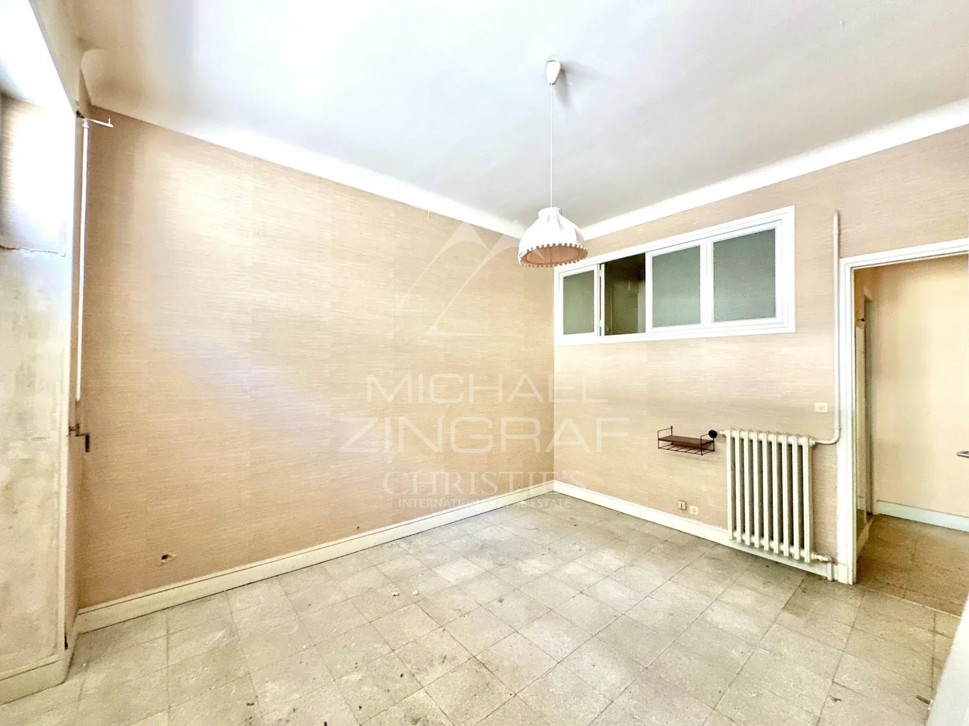 Appartement à réinventer à Nice Intérieur d'un appartement vide à Nice, murs clairs et sol carrelé, lumière naturelle.