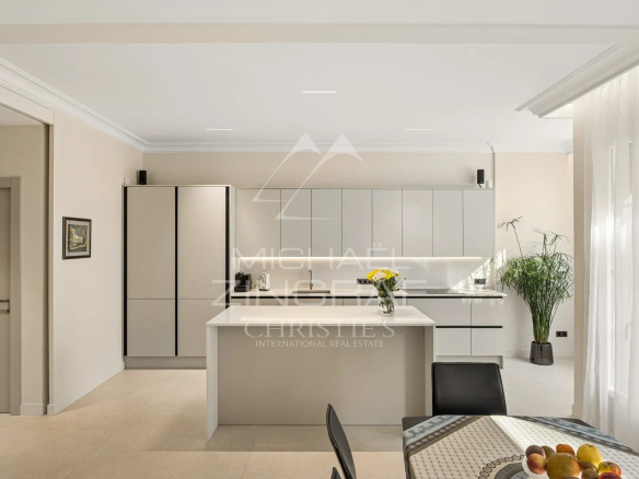 Cuisine moderne et lumineuse d'un appartement rénové avec un îlot central et des meubles clairs.