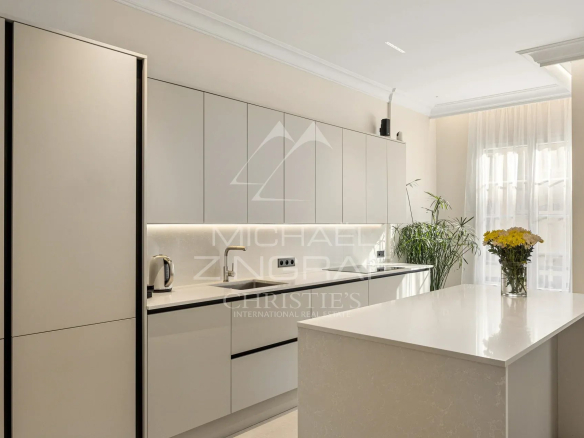Cuisine moderne et lumineuse d'un appartement rénové avec îlot central et équipements récents.