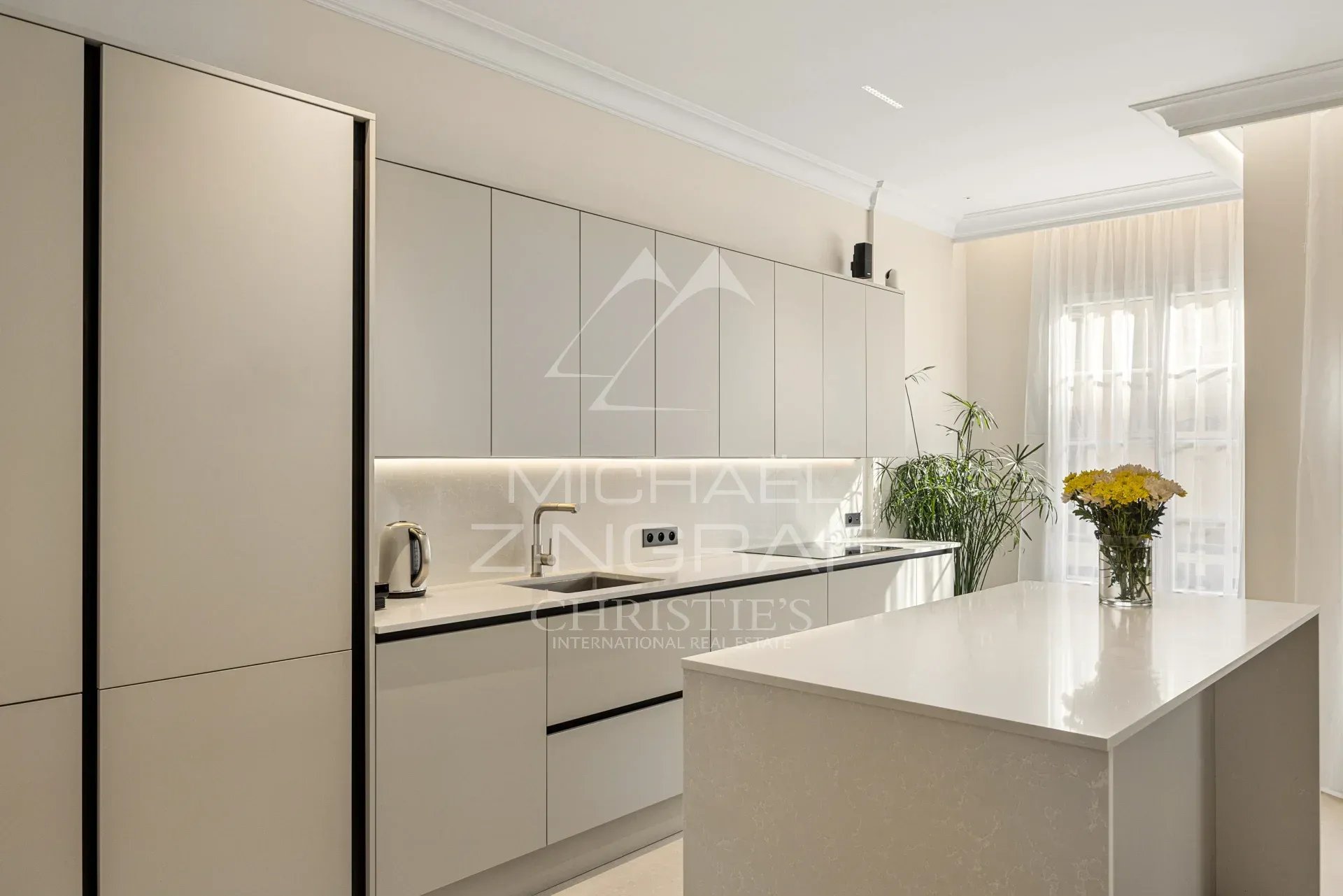 Cuisine moderne et lumineuse d'un appartement rénové avec îlot central et équipements récents.