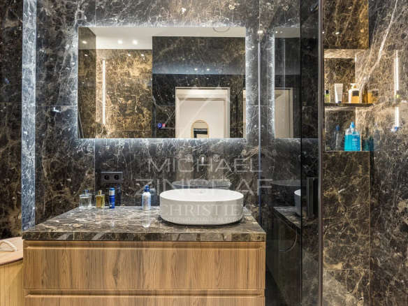 Salle de bain moderne avec marbre et lavabo sur meuble en bois.