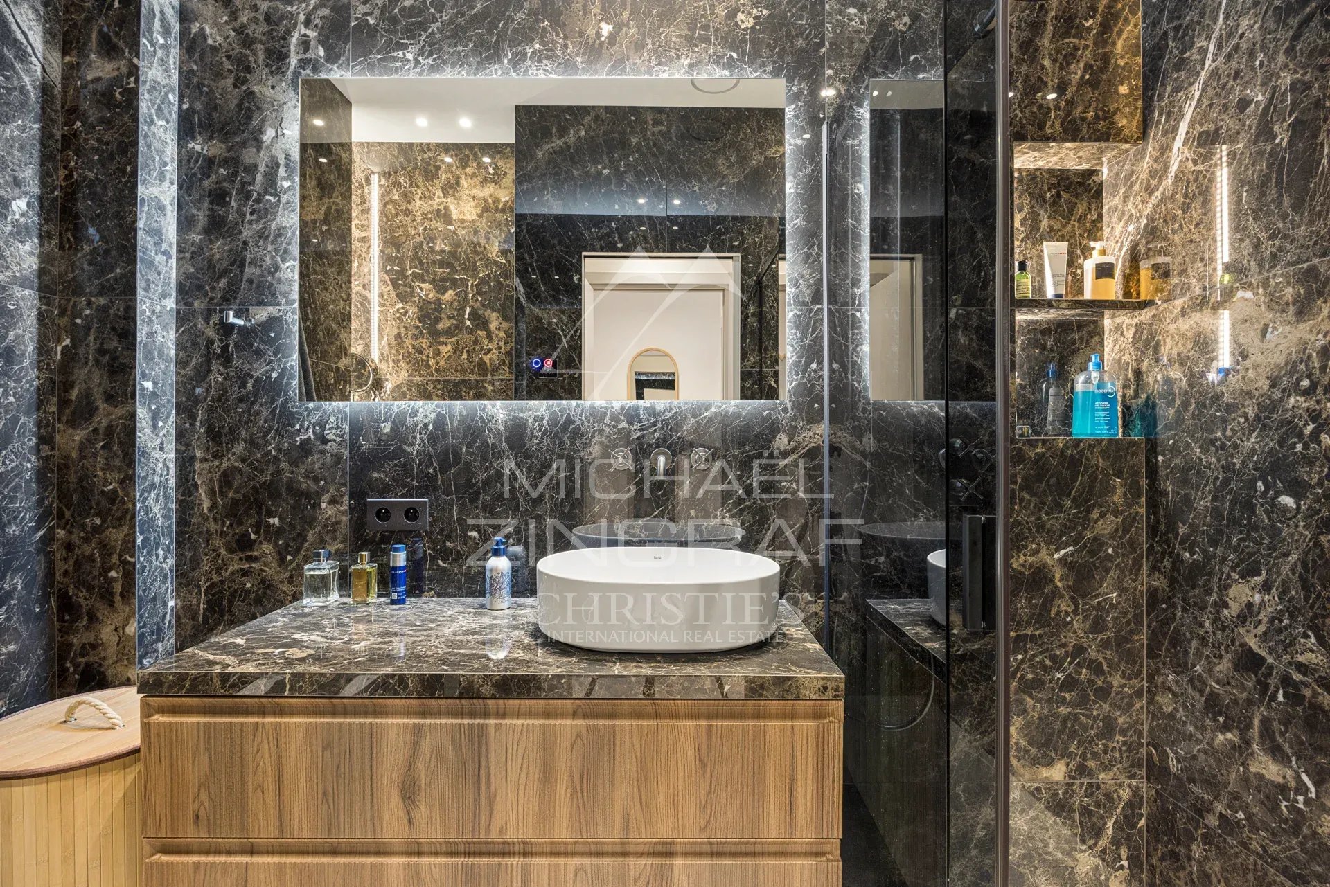 Salle de bain moderne avec marbre et lavabo sur meuble en bois.