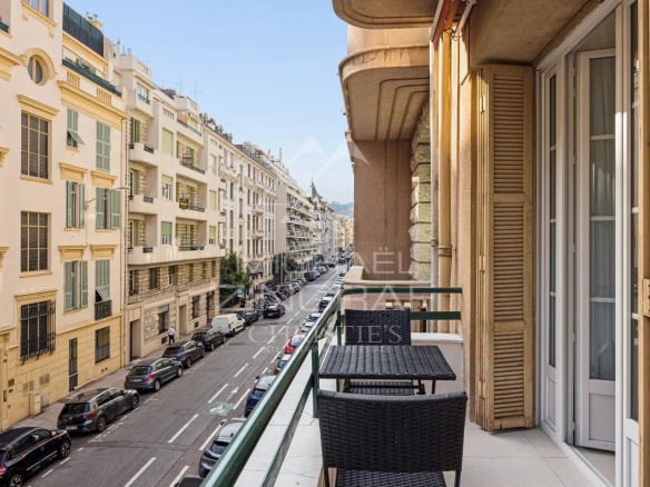 Balcon d'un appartement à Nice avec vue sur la rue, immeubles Art déco en arrière-plan.