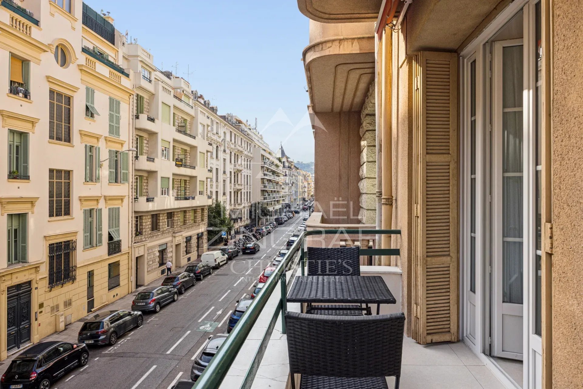 Balcon d'un appartement à Nice avec vue sur la rue, immeubles Art déco en arrière-plan.