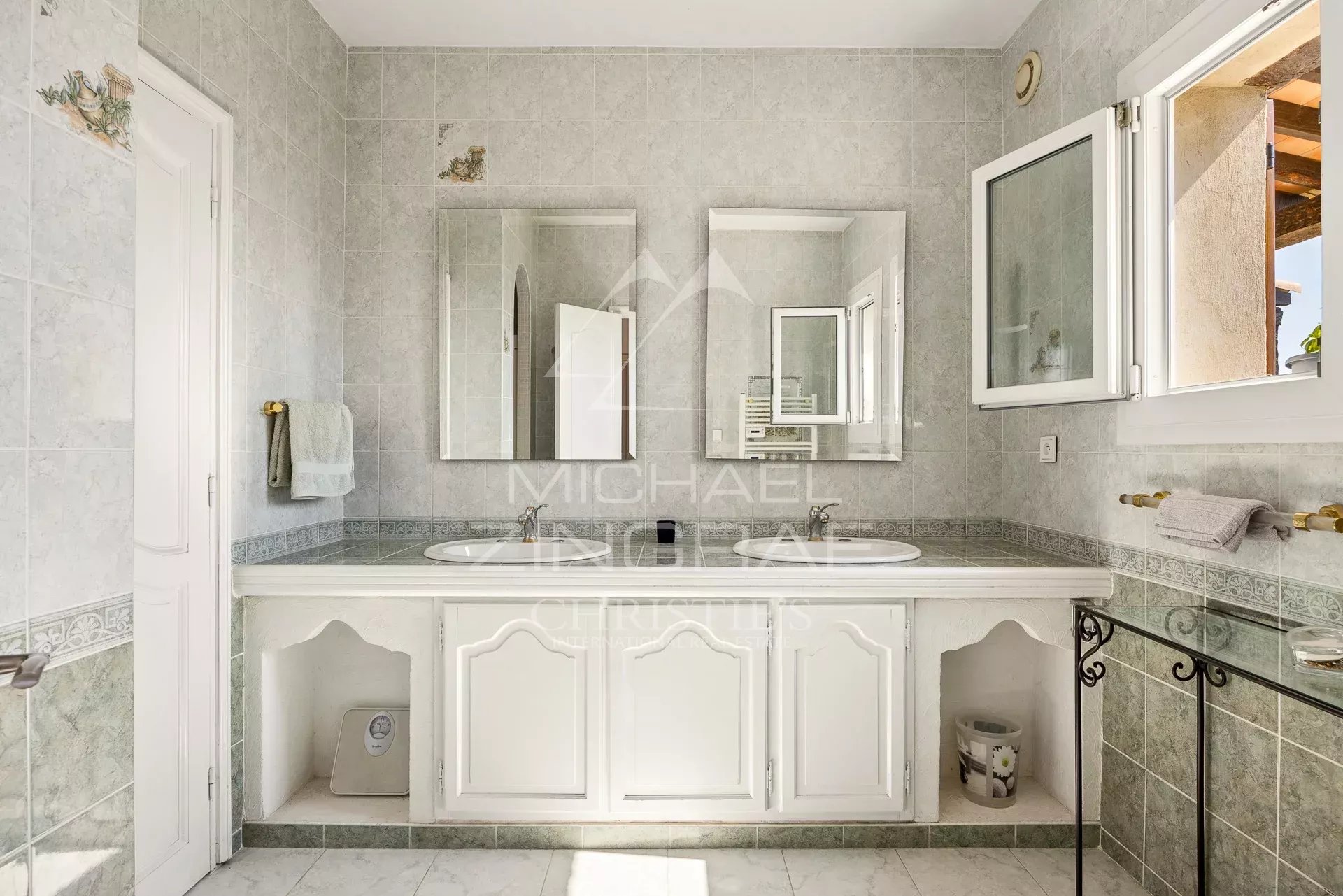 Elegant bathroom in Aspremont Spacious bathroom with double sink and mirrors, decorated with light-colored tiles.