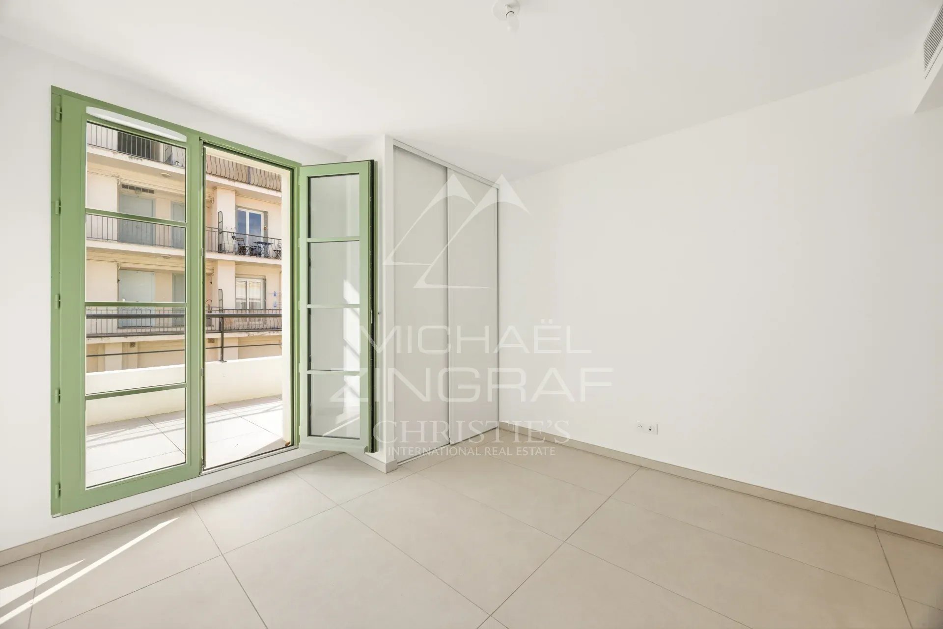Intérieur d'un appartement neuf à Nice avec fenêtres ouvertes sur un balcon.