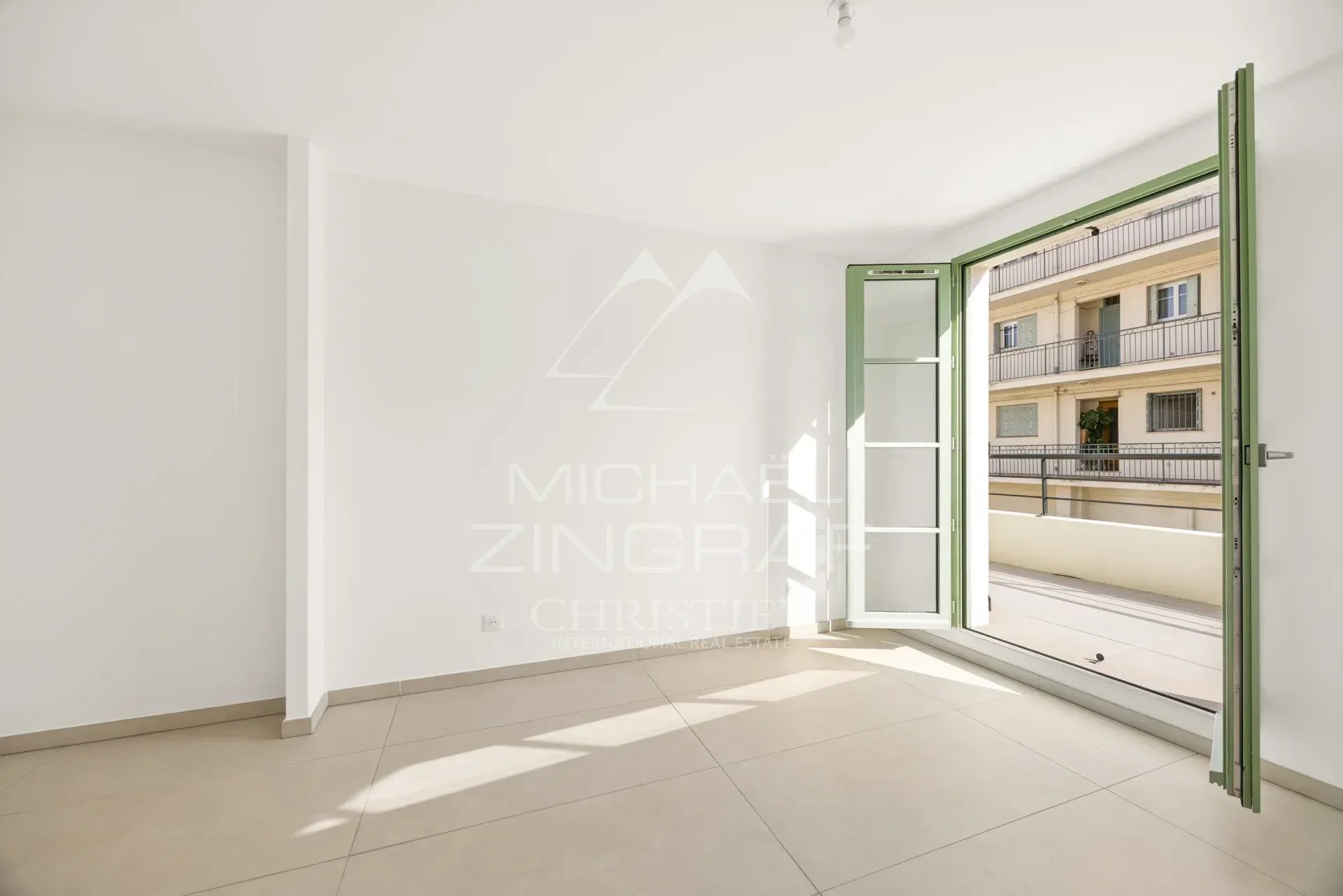 Intérieur d'un appartement neuf à Nice, avec une fenêtre ouverte sur une terrasse.