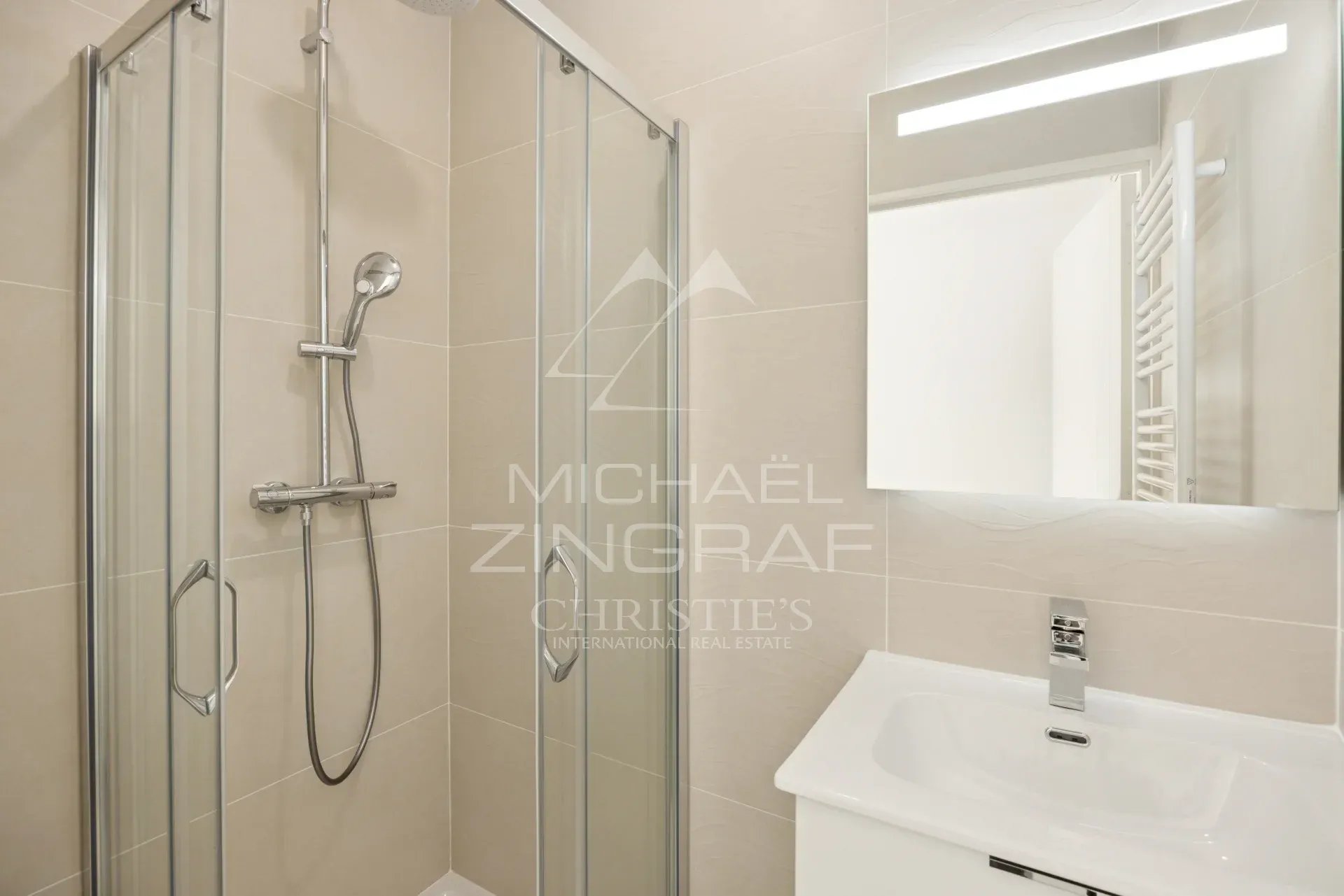 Salle de bain moderne avec douche vitrée et lavabo dans un appartement neuf à Nice.