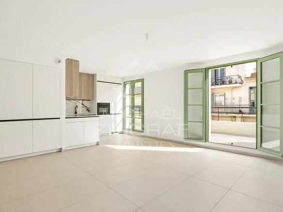 Intérieur d'un appartement neuf à Nice avec fenêtres ouvertes et cuisine intégrée.