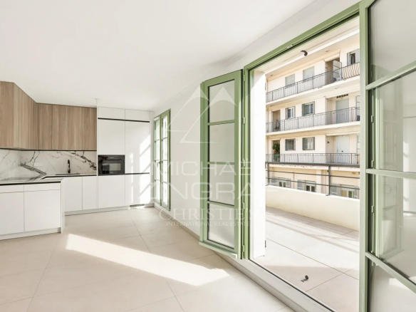 Intérieur d'un appartement moderne avec cuisine ouverte et grandes fenêtres à Nice.