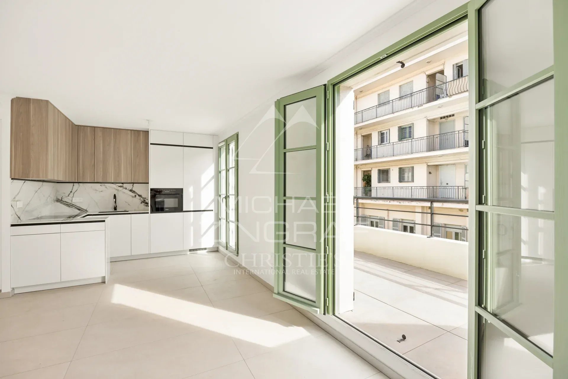 Intérieur d'un appartement moderne avec cuisine ouverte et grandes fenêtres à Nice.