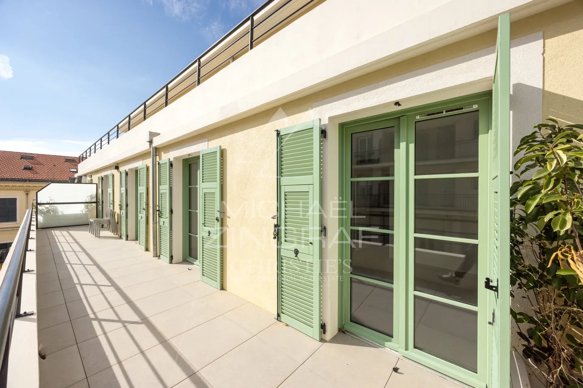Terrasse d'un appartement avec volets verts à Nice, ensoleillée et spacieuse.