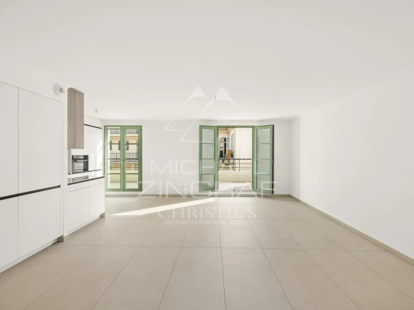 Intérieur d'un appartement moderne et lumineux à Nice, avec fenêtres ouvertes et carrelage clair.