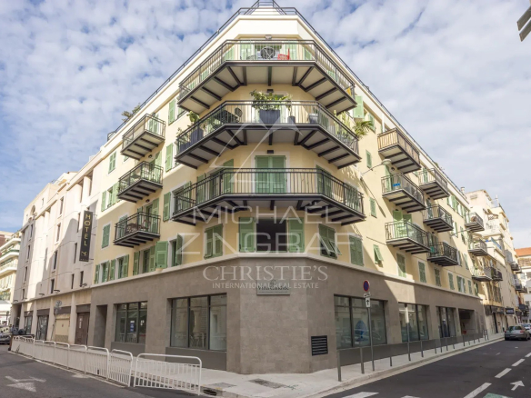 Immeuble moderne à Nice avec balcons et terrasse, situé dans un quartier animé.