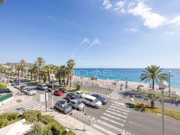 View of the Promenade des Anglais and the sea in Nice, with palm trees and cars on the road.