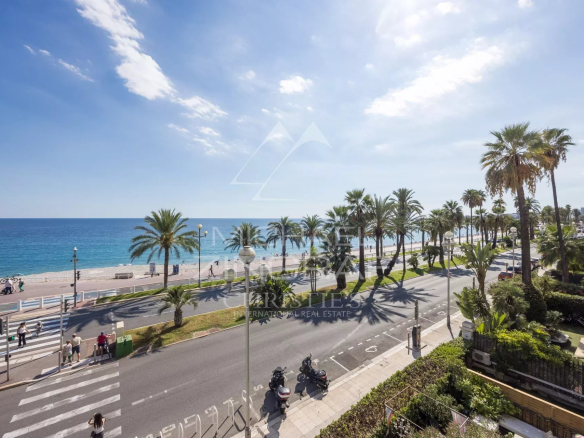 View of the Promenade des Anglais and the sea in Nice, with palm trees and cars on the road.